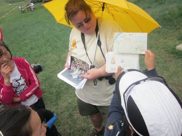 Getting some shade under an umbrella while teaching kids in Mongolia with postcards from my students in Michigan.